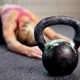 14158006-young-woman-stretching-her-back-after-a-heavy-kettlebell-workout-in-a-gym